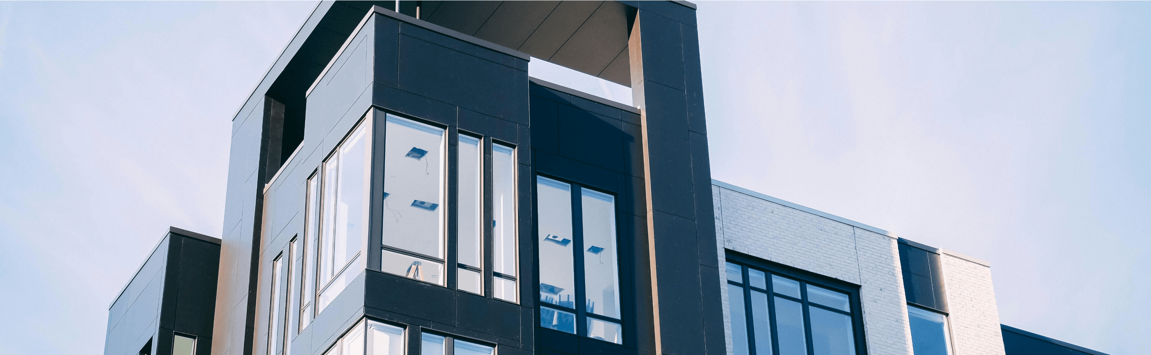 Background image showing modern buildings featuring floor-to-ceiling windows and aluminum cladding on the exterior